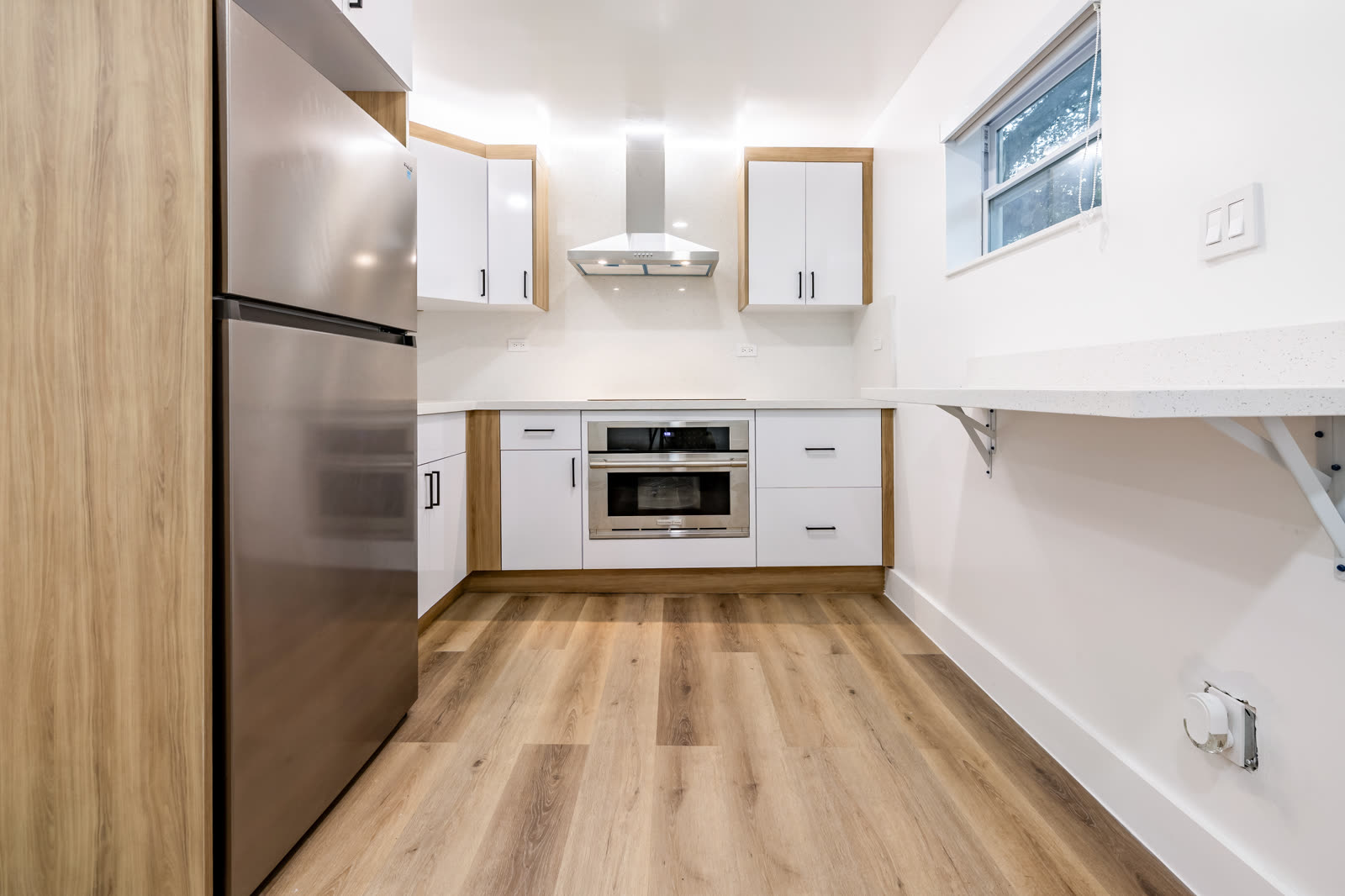 Kitchenette: white and wood cabinets, a built-in oven and a fold-down counter
