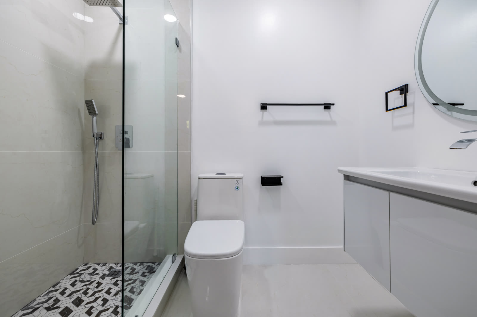 Bright, clean bathroom: frameless glass, a patterned shower floor and matte black fixtures