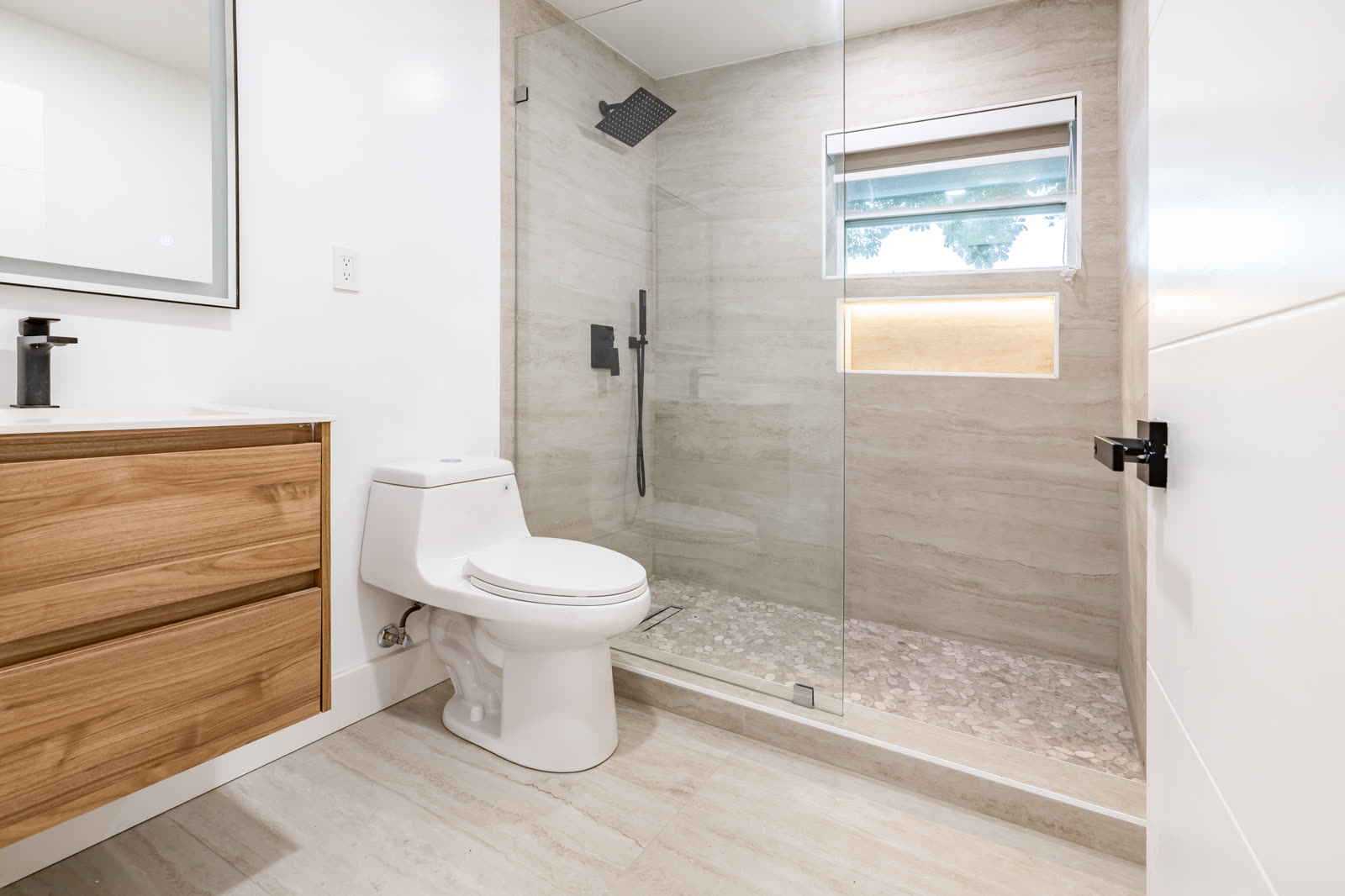 Walk-in shower: floor-to-ceiling tile, a lit niche and a floating wood vanity