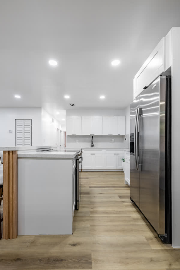 Kitchen with white cabinets, a fluted wood island and bar seating