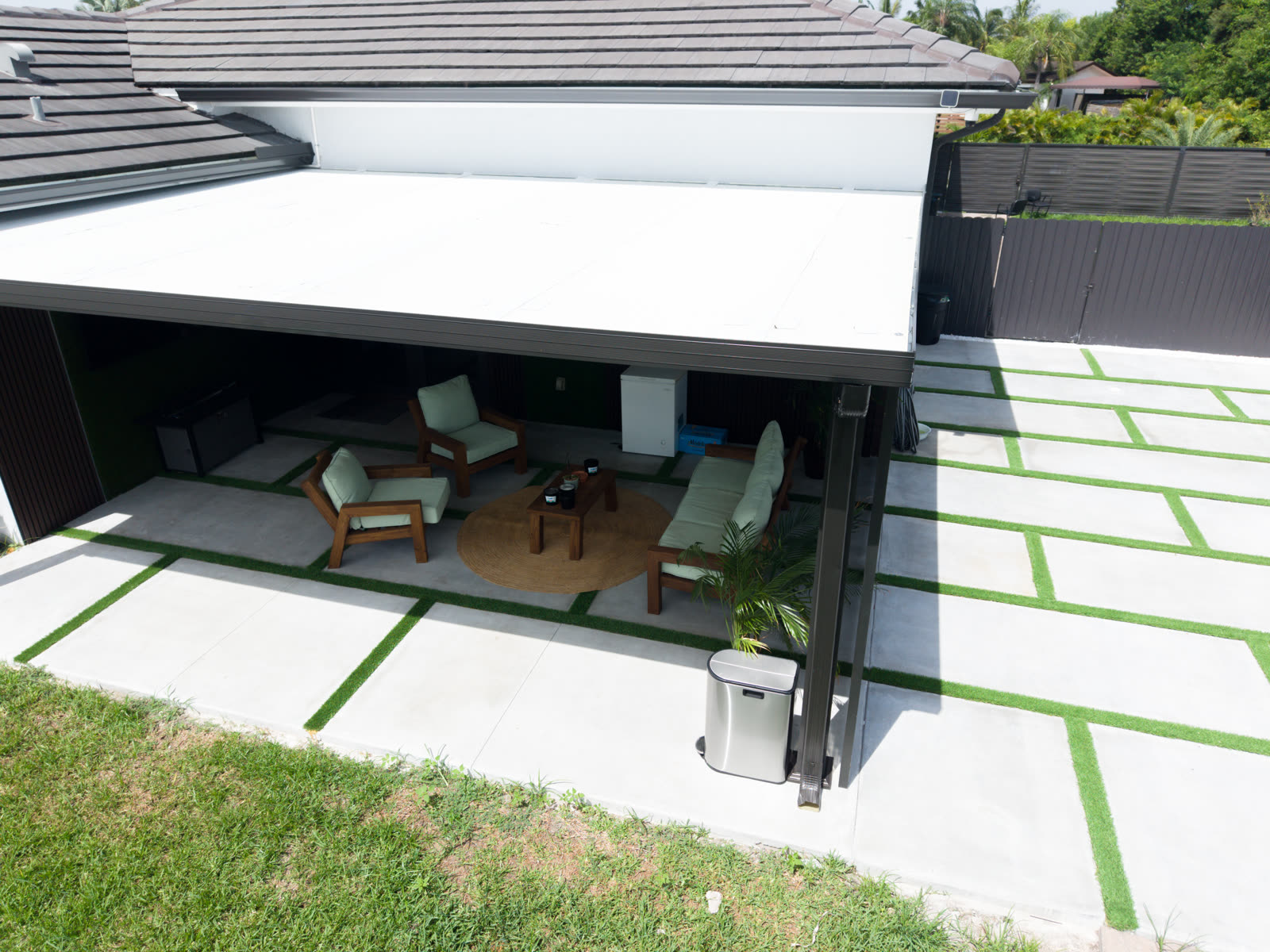 Covered outdoor lounge: insulated white roof panels over a paver and turf patio